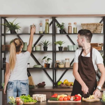 Bucătărie pe balcon: femeie organizând rafturi, bărbat gătind